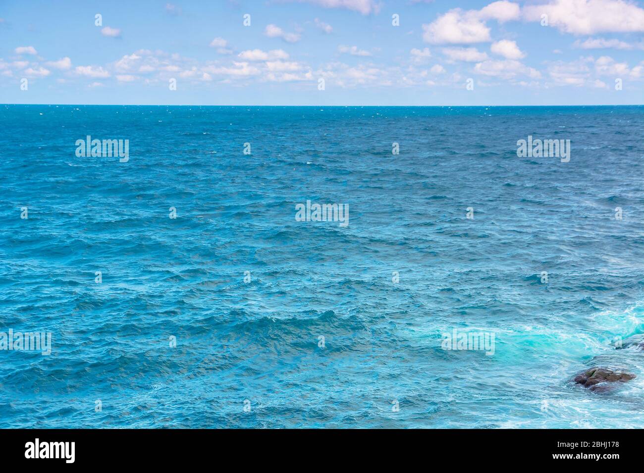 rocky sea shore in the afternoon. blue waves crashing the coast. fluffy ...