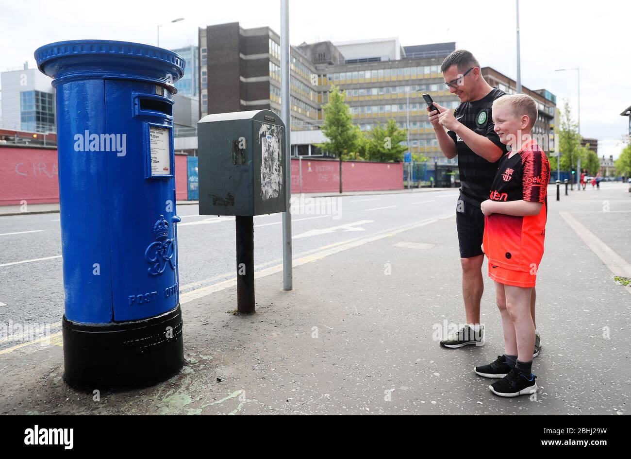 Paul Moore, a cleaner at the Royal Victoria Hospital, with his son Kayden Parker (10) photographs a post box outside the Hospital on the Falls Road, Belfast, which has been painted blue in support of the NHS health care workers. Stock Photo
