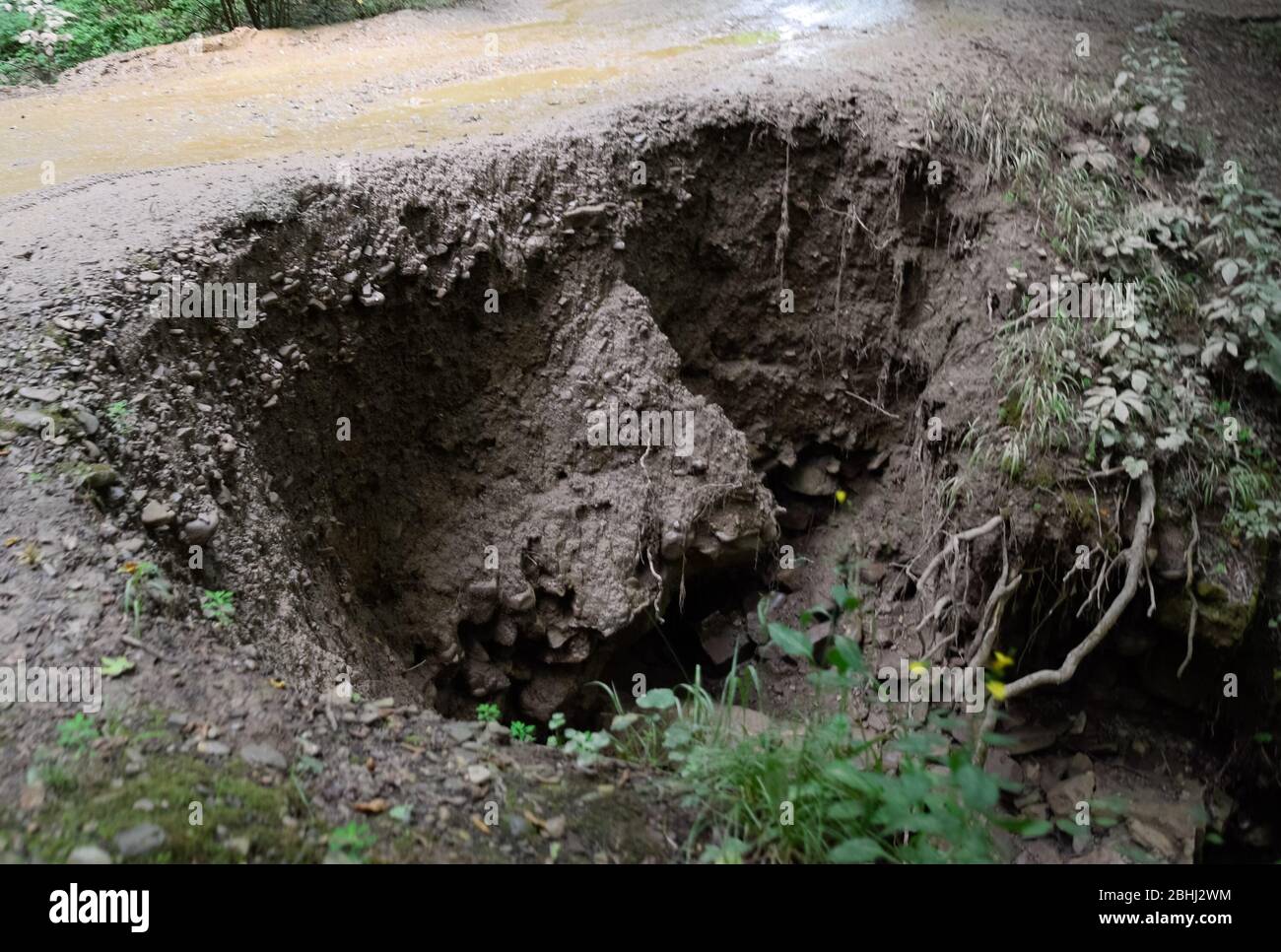 The collapsed edge of the road from the rain. Akyduct for water runoff. Stock Photo