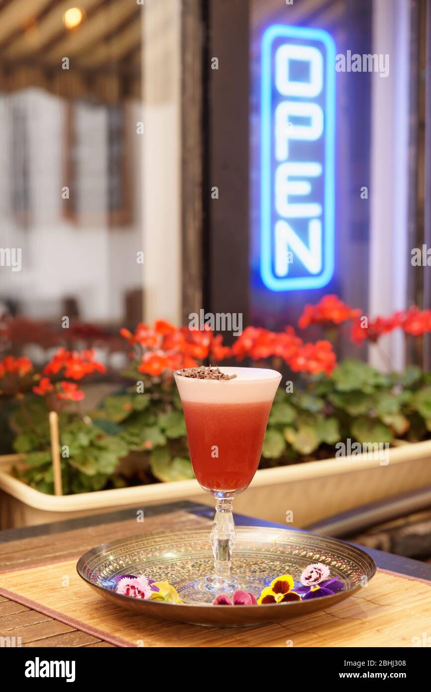 Red flip cocktail with froth and chocolate on table in bar or restaurant Stock Photo