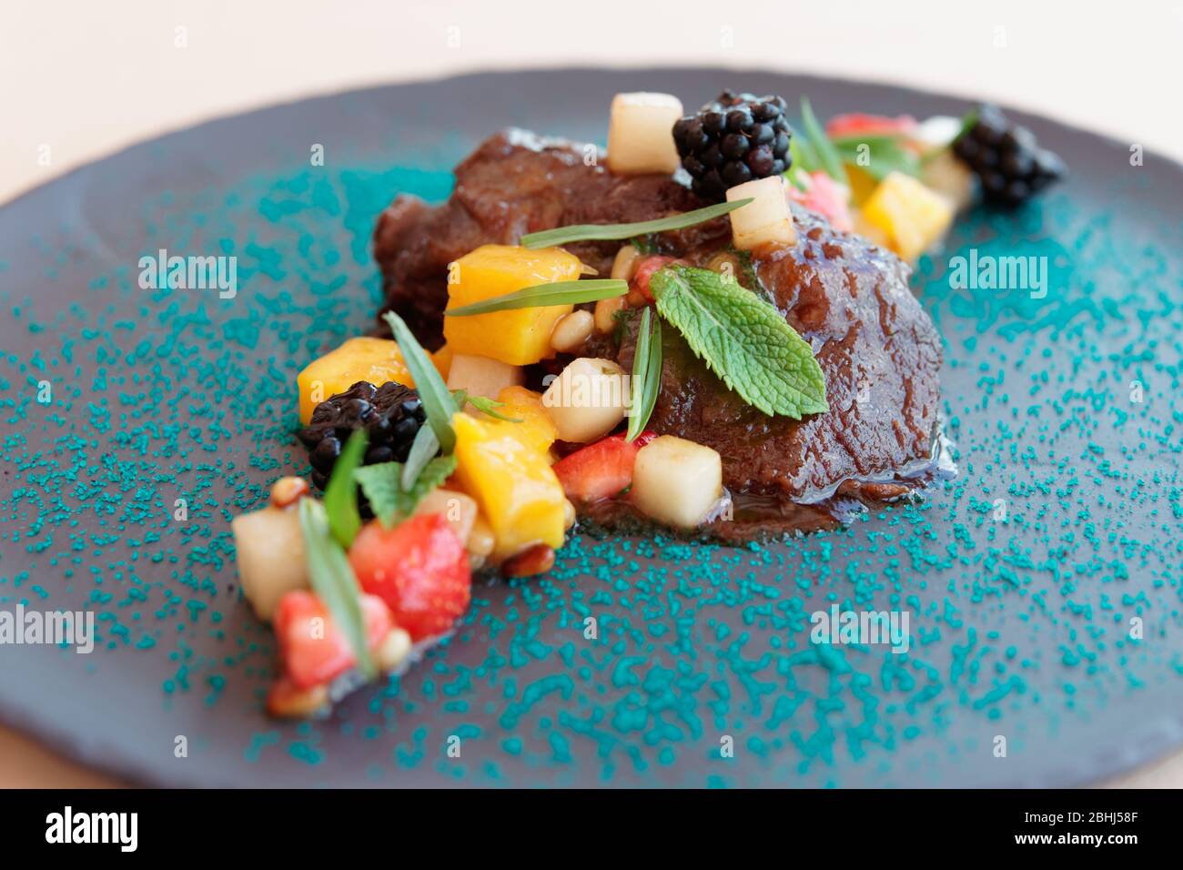 Slowcooked veal cheek with fruits and berries, closeup Stock Photo