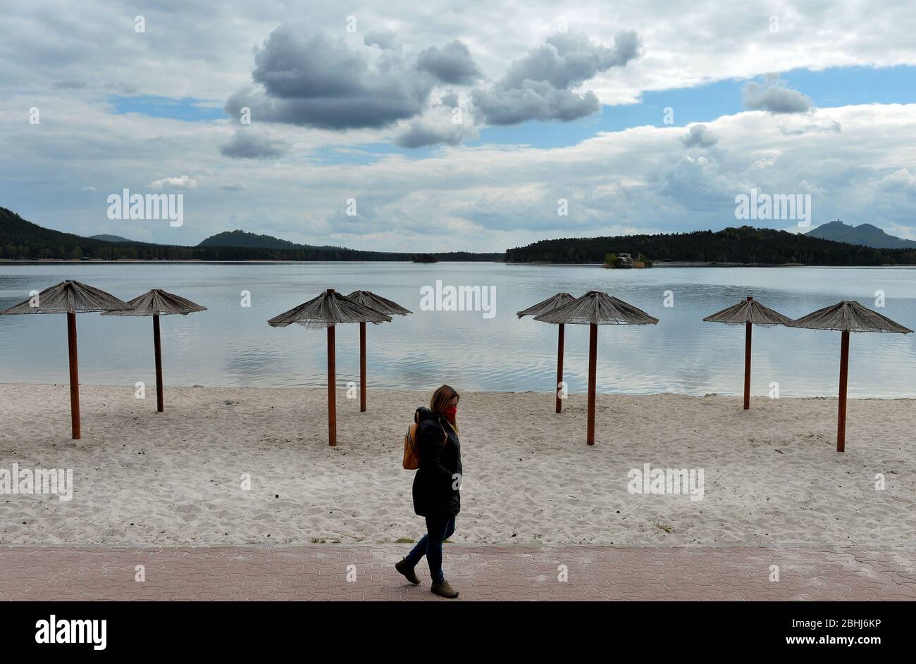 Stare Splavy, Czech Republic. 26th Apr, 2020. A woman wearing protective face mask strolling along the Lake Macha coast (95 kilometers north from Prague) in the Czech Republic. The Czech Republic government starting to ease restrictions. The first, slow steps towards a return to normal life have been taken. Still, the rules for social distancing and mandatory wearing of face masks remain in place. Credit: Slavek Ruta/ZUMA Wire/Alamy Live News Stock Photo