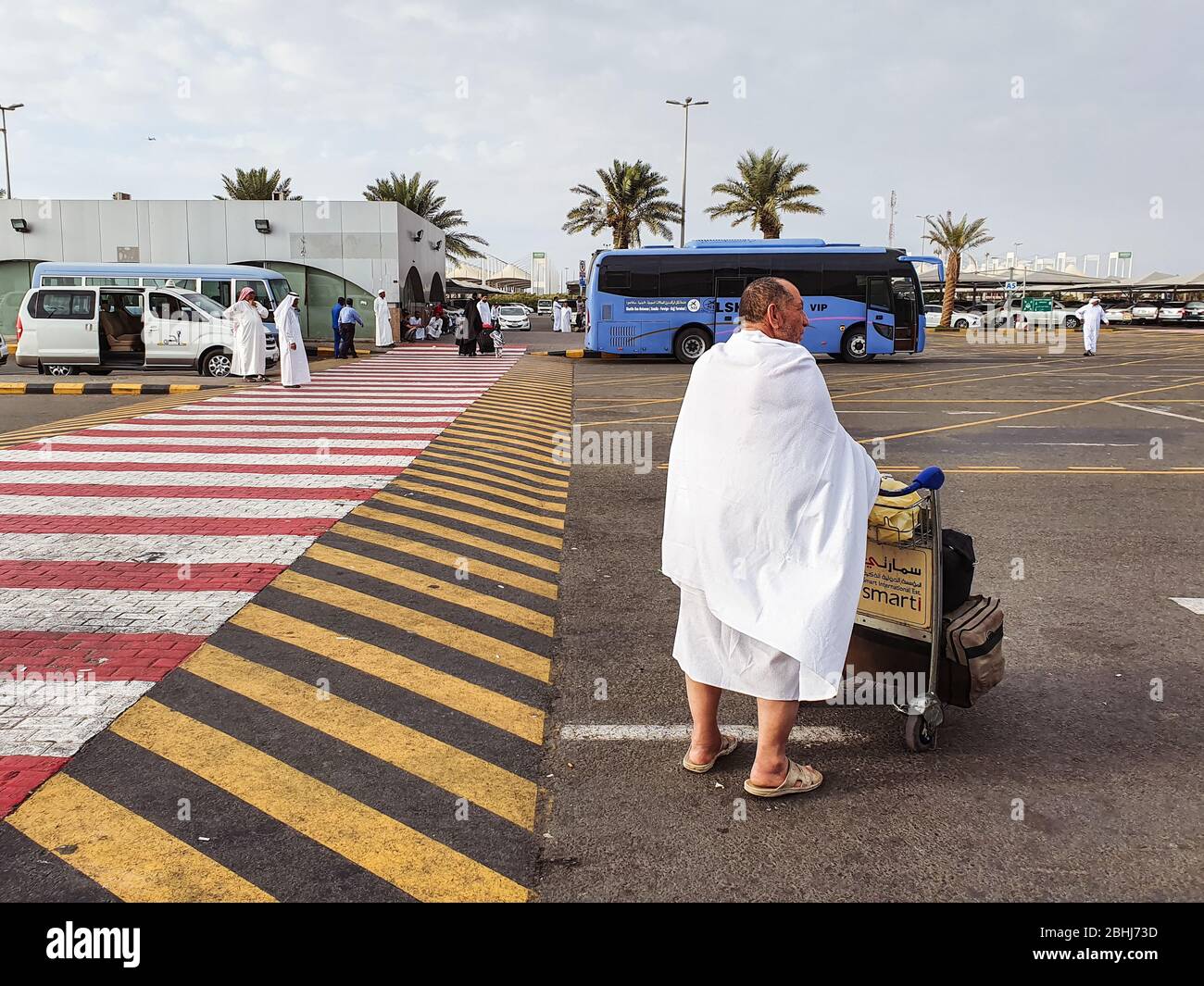 Jeddah / Saudi Arabia - January 16, 2020: Muslim man pushing lugage while wearing white clothes similar to towels outside Jeddah airport Stock Photo