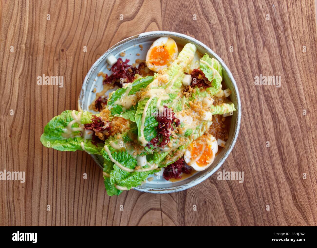 Caesar salad cooked in Asian way, shot from above Stock Photo