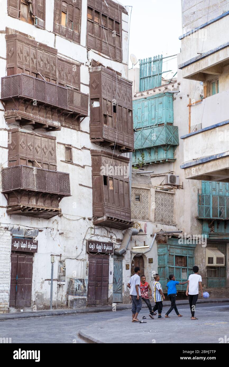 Jeddah / Saudi Arabia - January 16, 2020: people next to colorful architecture historical buildings on the streets of Al-Balad Stock Photo