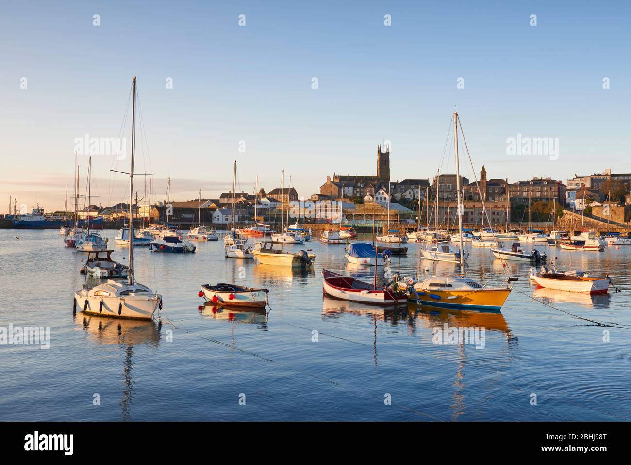 The first light of the morning sun shining over Penzance Harbour Stock Photo
