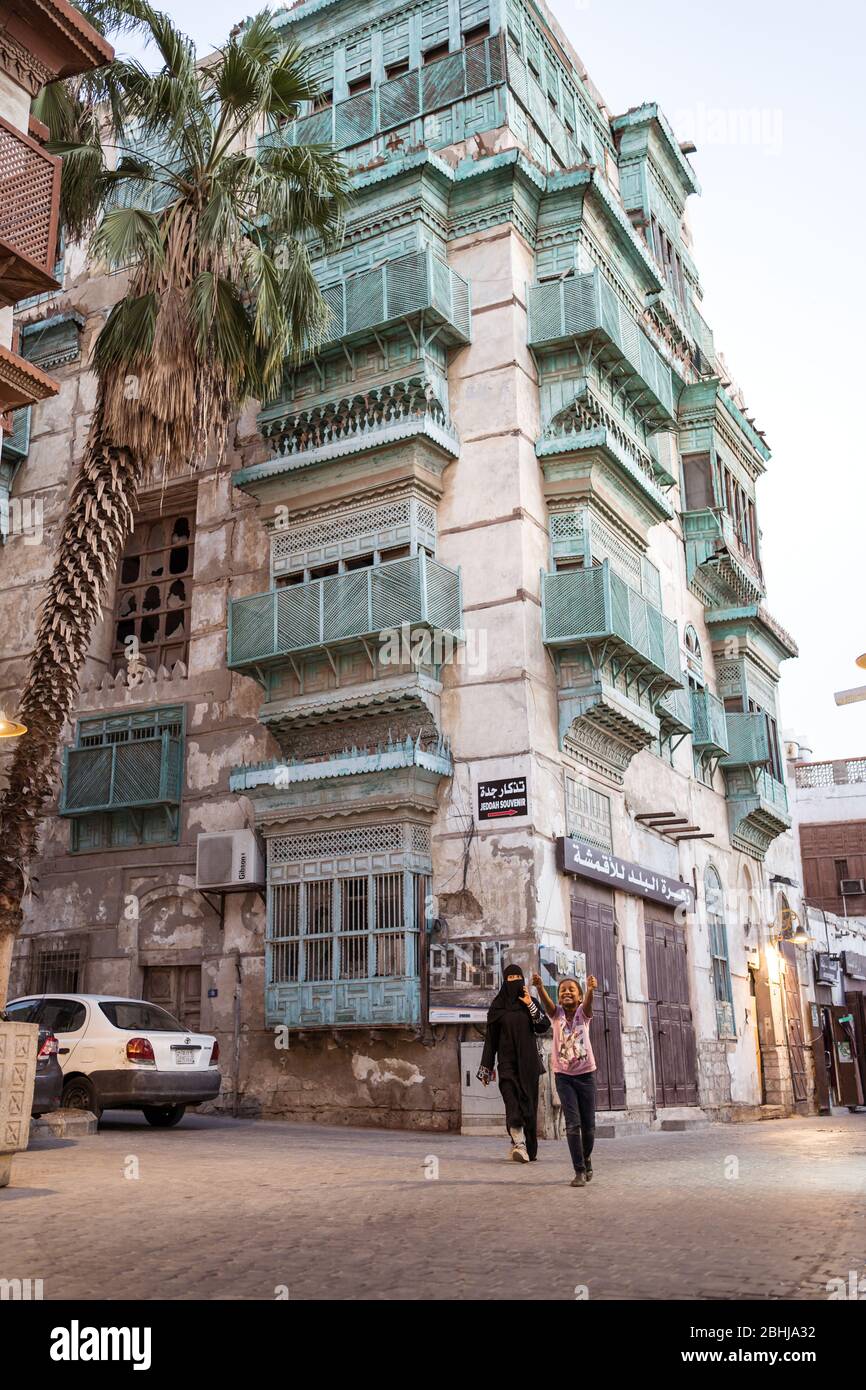 Jeddah / Saudi Arabia - January 16, 2020: Mother and daugther walking in front of historic colorful building in Al-Balad Stock Photo