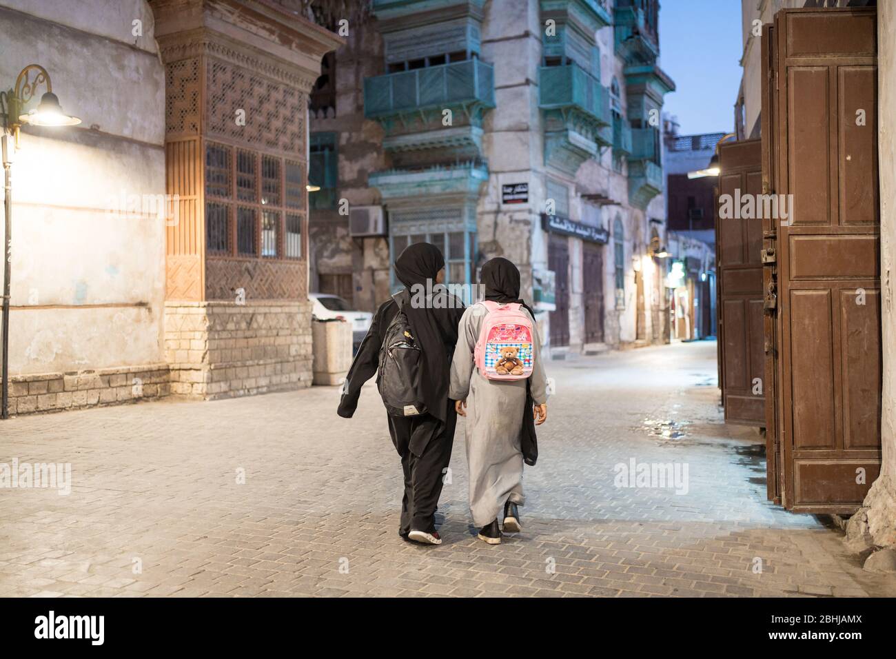 Jeddah / Saudi Arabia - January 16, 2020: Muslim girls with backpacks walking after school in the street of historic Al-Balad Stock Photo