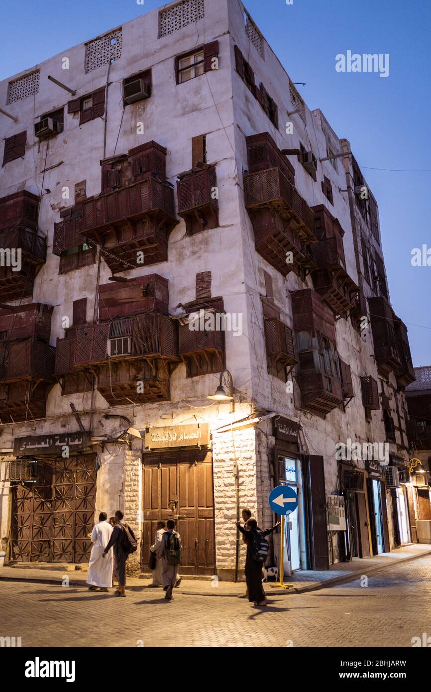 Jeddah / Saudi Arabia - January 16, 2020: Night view of street of old town historic Al-Balad with people walking and wooden balconies in buildings Stock Photo