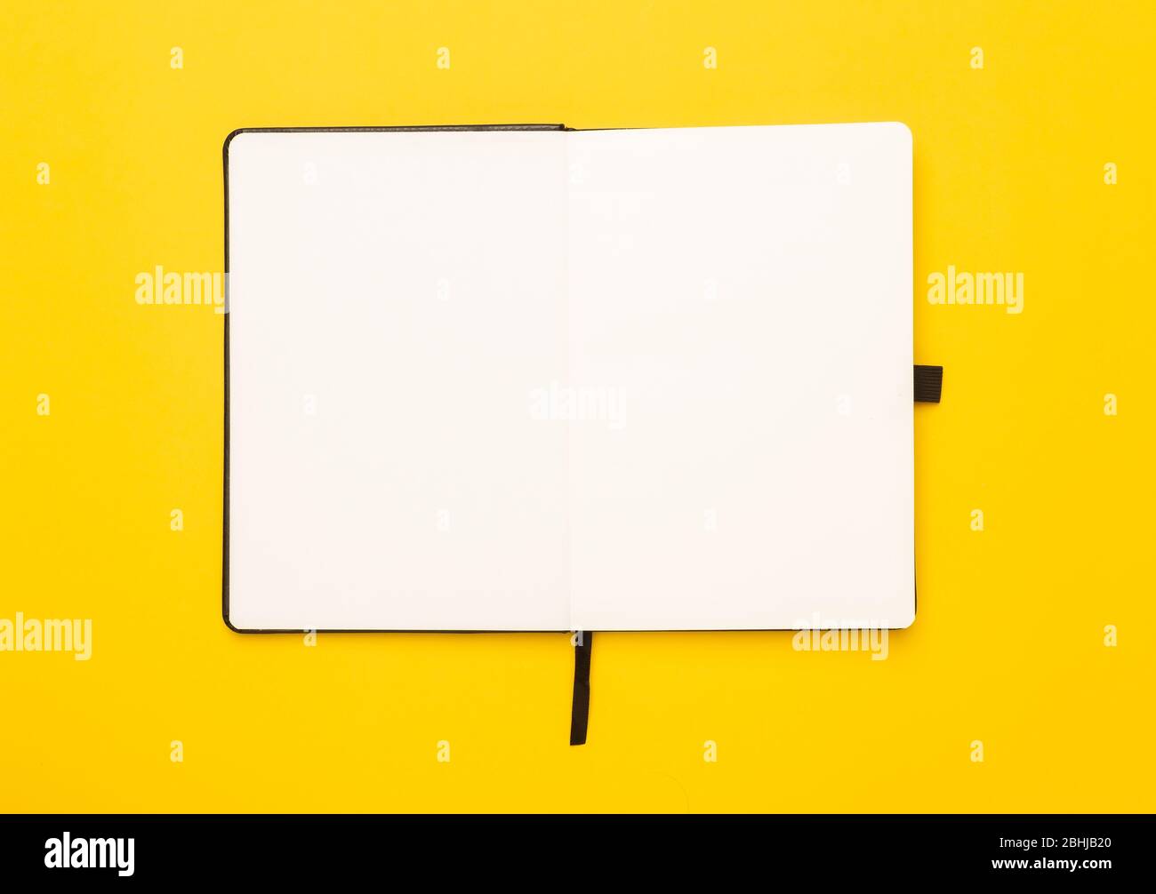 Black notebook opened isolated on yellow background. Stock Photo
