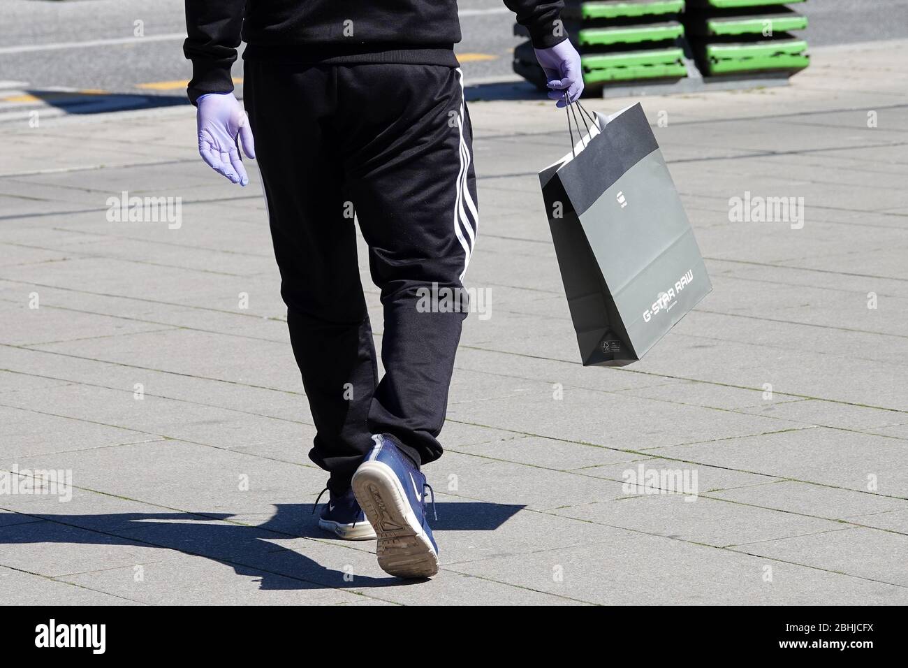 Hamburg, Germany. 20th Apr, 2020. A passer-by wearing plastic gloves and a G -Star Raw shopping bag is walking through downtown Hamburg. Credit: Bodo  Marks/dpa/Alamy Live News Stock Photo - Alamy
