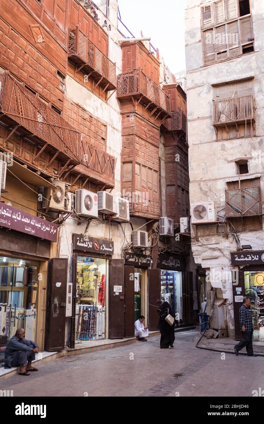 Jeddah / Saudi Arabia - January 16, 2020: Muslim women wearing abaya walking in front of wooden building in historic Al-Balad old town Stock Photo