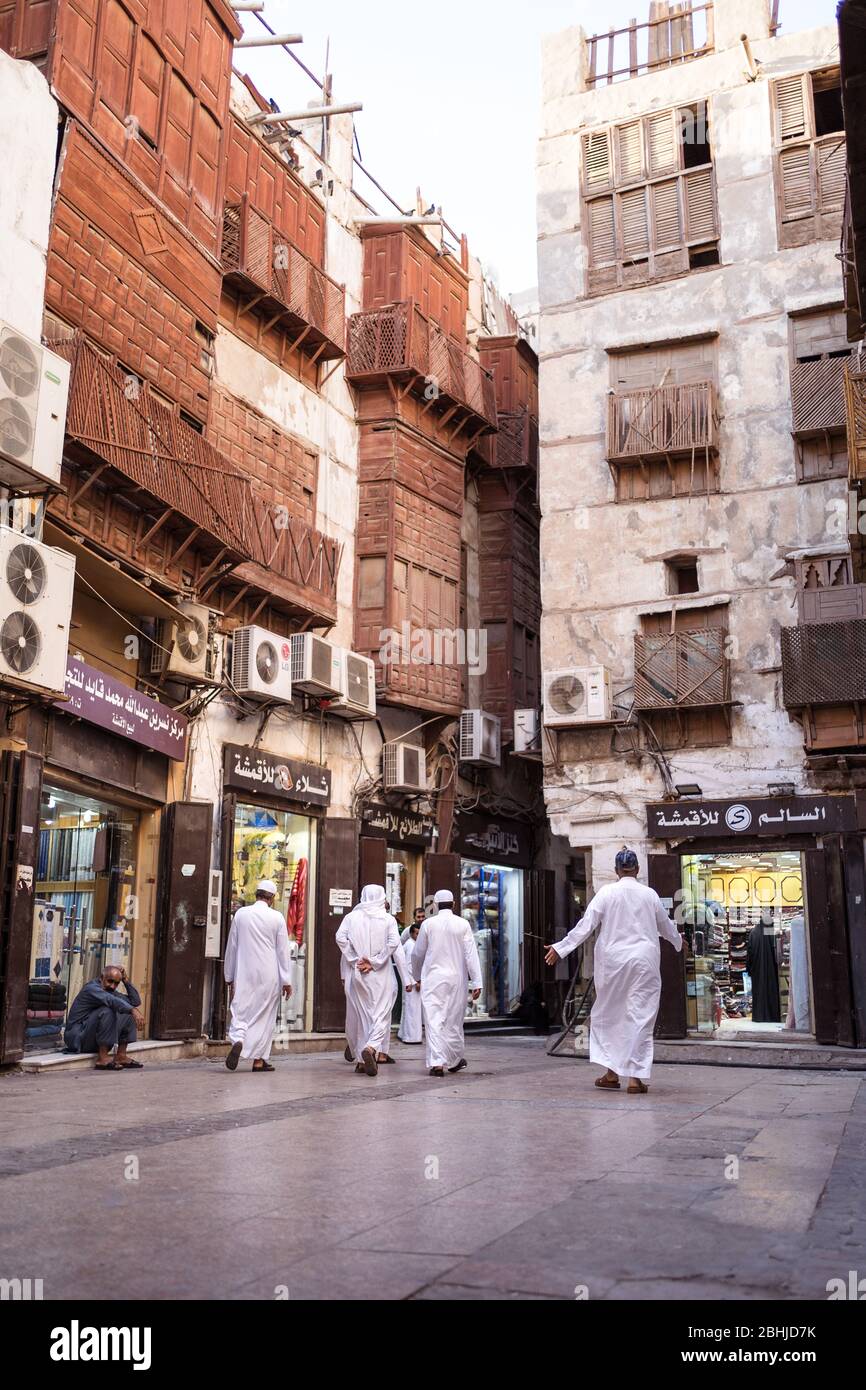 Jeddah / Saudi Arabia - January 16, 2020: Muslim man wearing traditional Muslim clothes walking in front of wooden building in historic Al-Balad Stock Photo