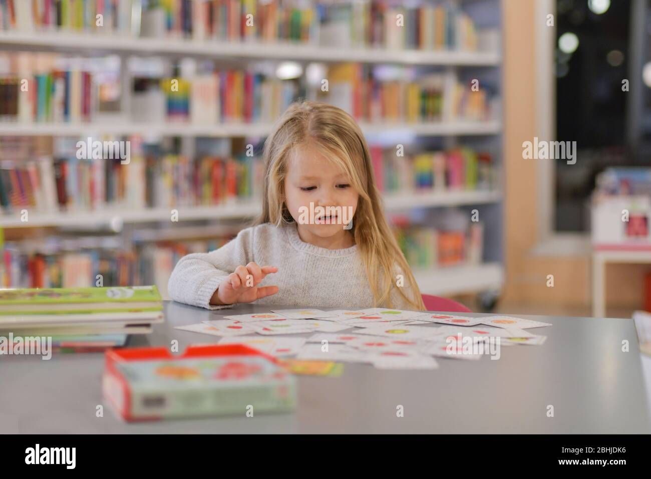 Little girl playing games in a library Stock Photo - Alamy