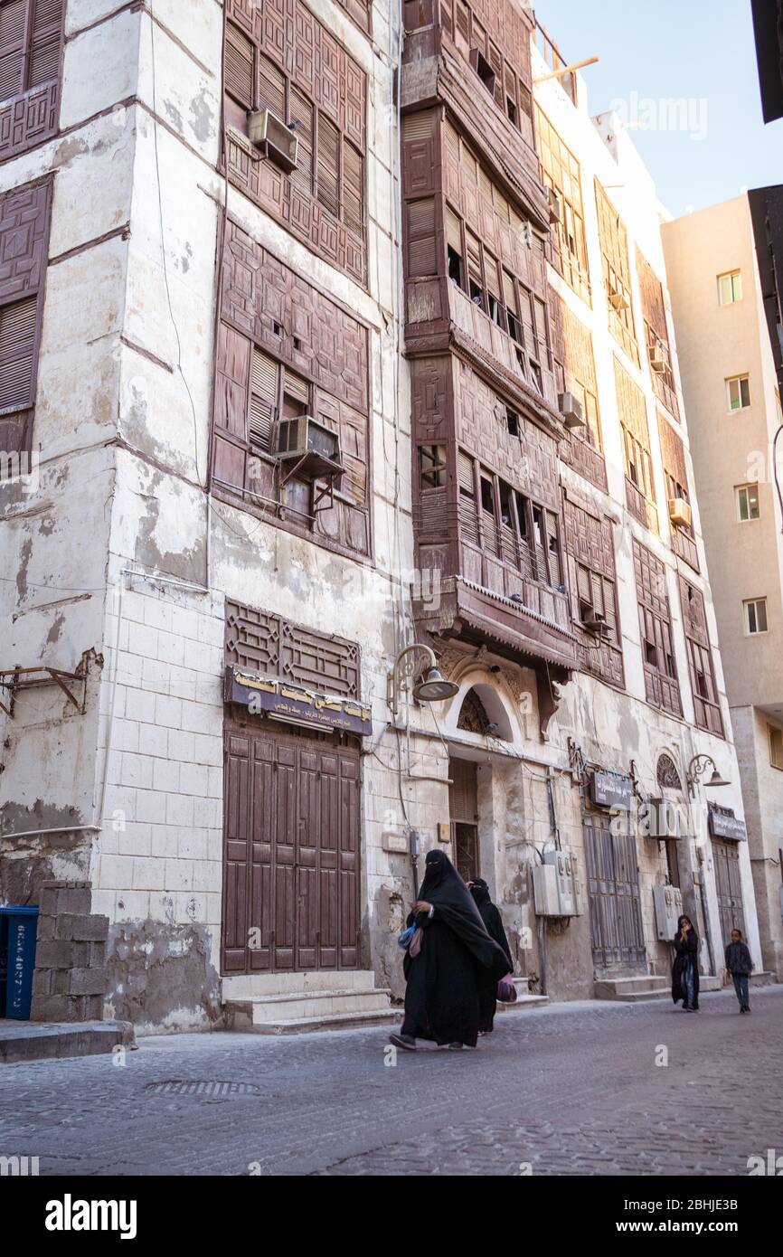 Jeddah / Saudi Arabia - January 16, 2020: Muslim women wearing abaya walking in front of historic wooden building in Al-Balad UNESCO historic Stock Photo