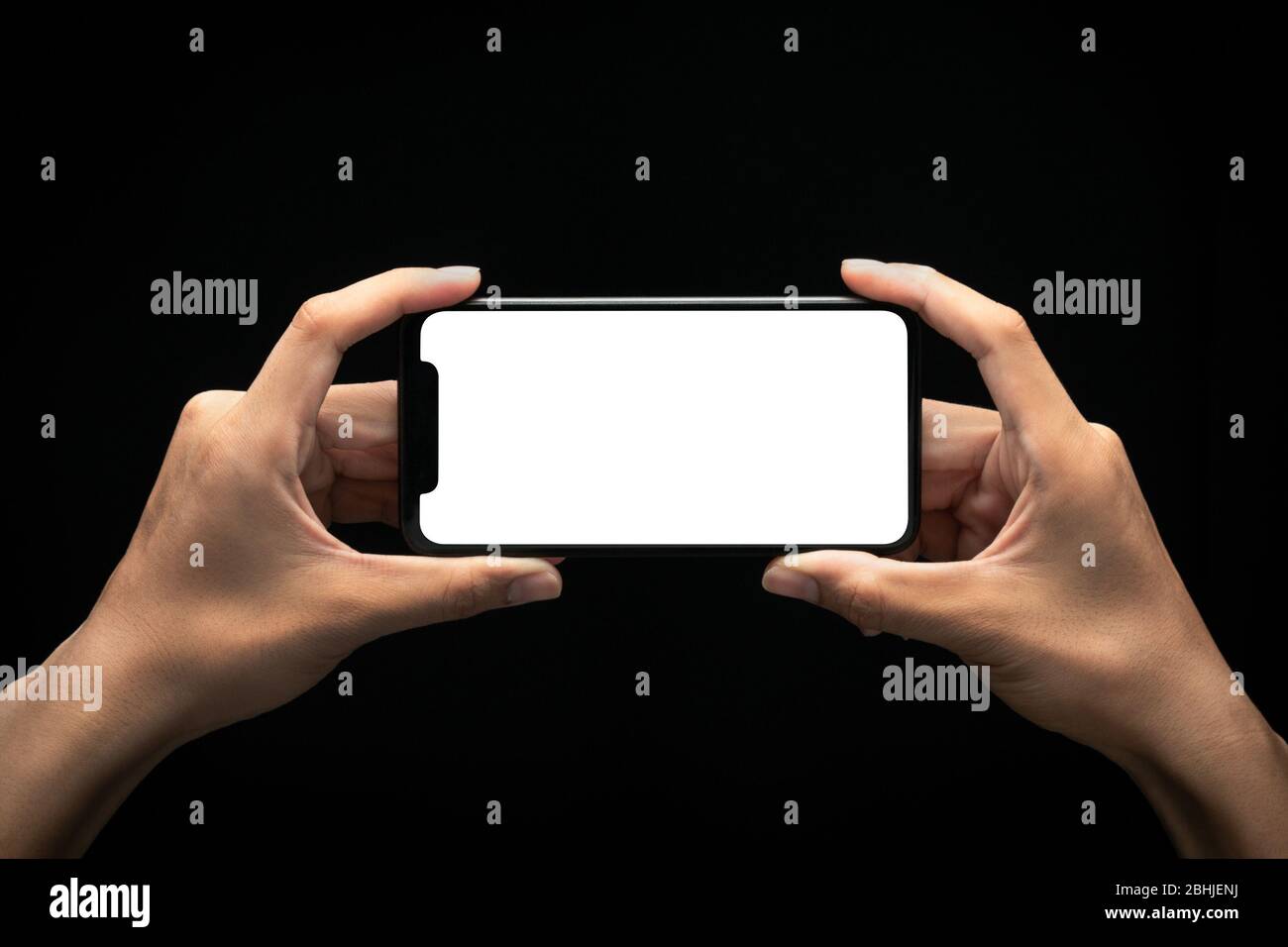 Male hands holding smartphone with blank screen at night over black ...
