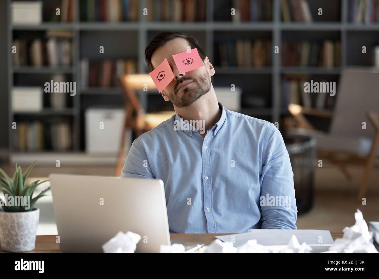 Exhausted tired businessman with stickers on eyes sleeping at workplace Stock Photo