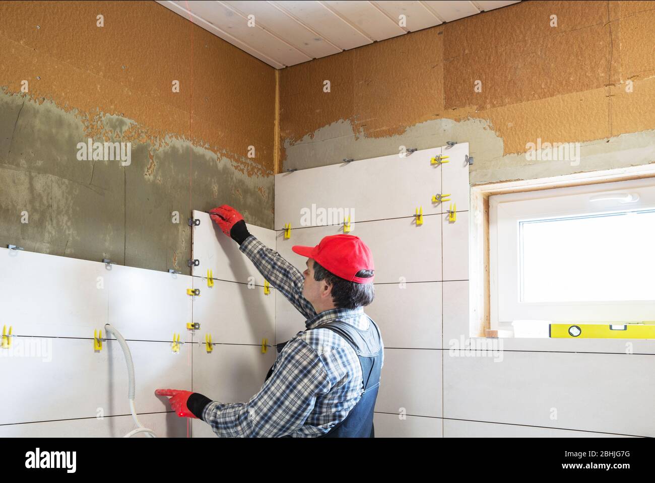 A worker installs ceramic tiles, building a house Stock Photo