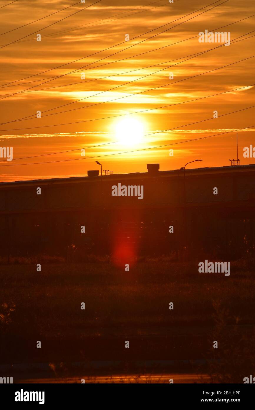 The bright orange color of the sunset illuminates the semi-urban landscape Stock Photo