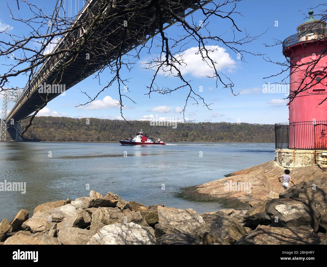New York, USA. April 2020. New York fire department boat underway on River Hudson under George Washington Bridge from the Little Red Lighthouse. Jeffr Stock Photo
