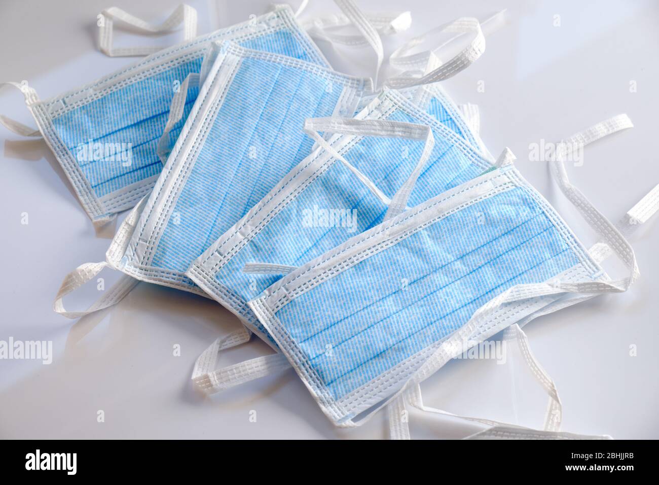 A stack of disposable face masks lying on white ground. Seen in Germany in April. Stock Photo