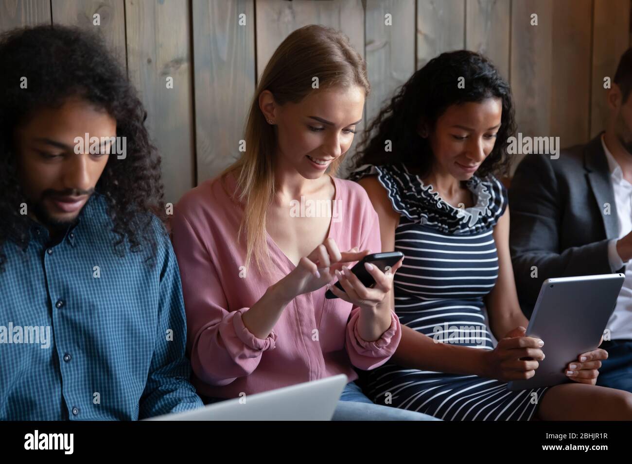 Multiracial young people relax on sofa using devices Stock Photo