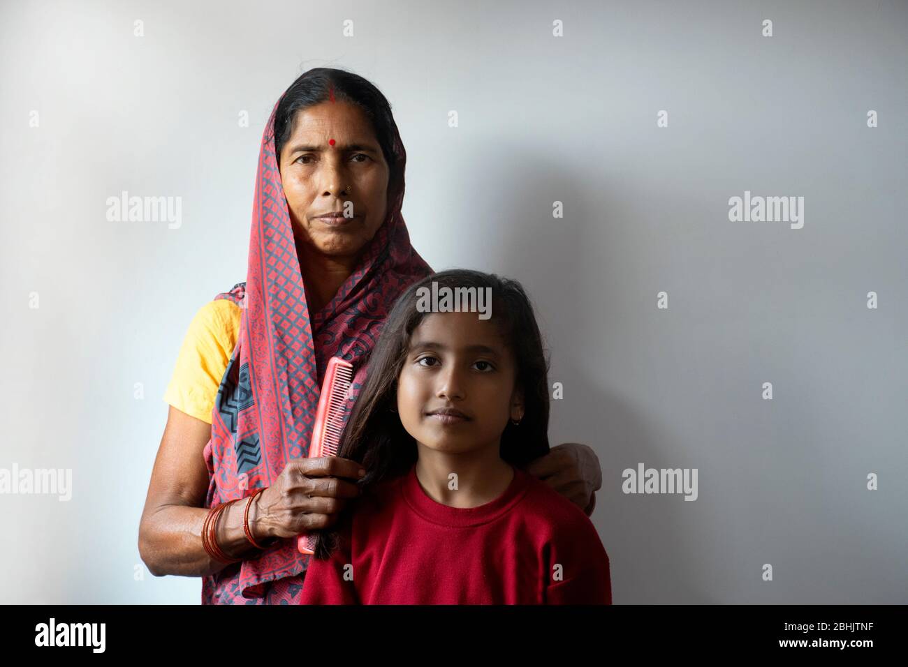 Grandmother combing  granddaughter hairs with love Stock Photo