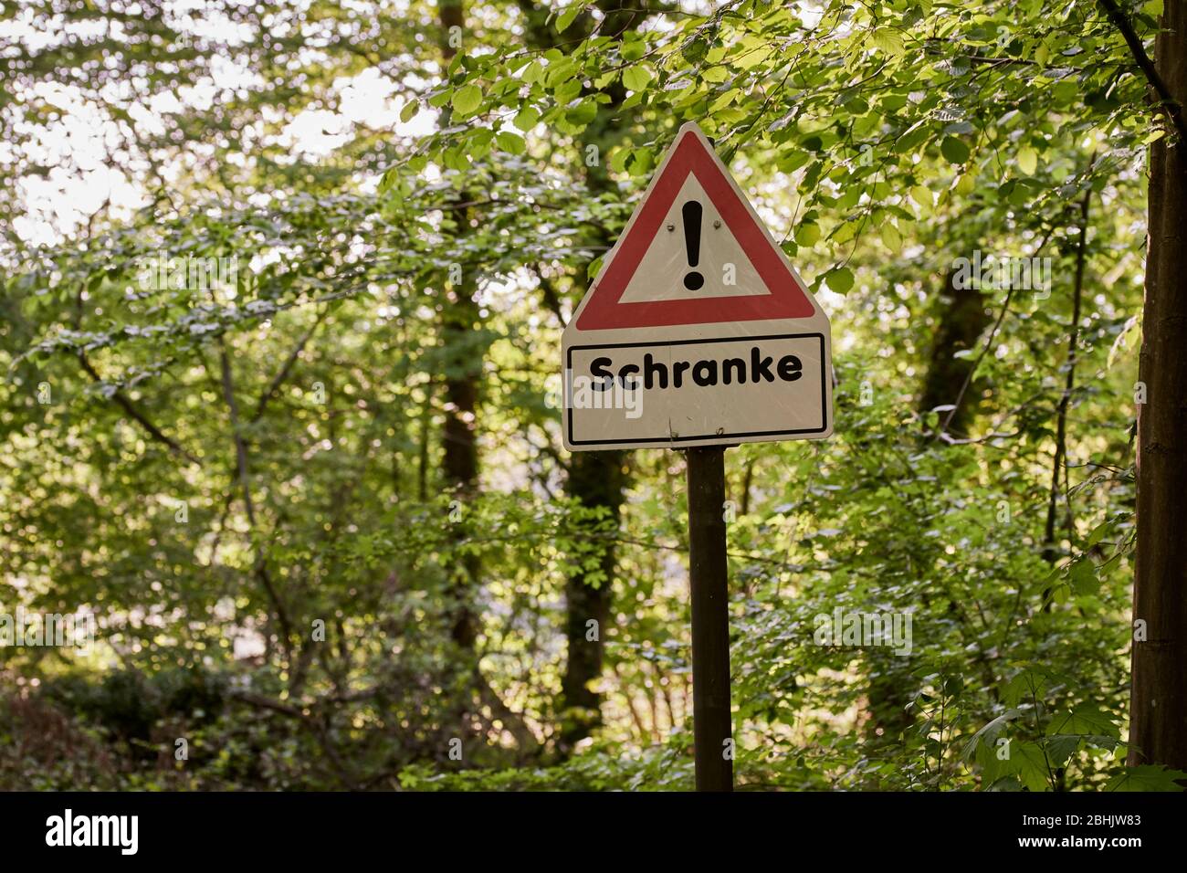 A red and white warning sign for a railroad crossing gate in the forest on a sunny spring day Stock Photo