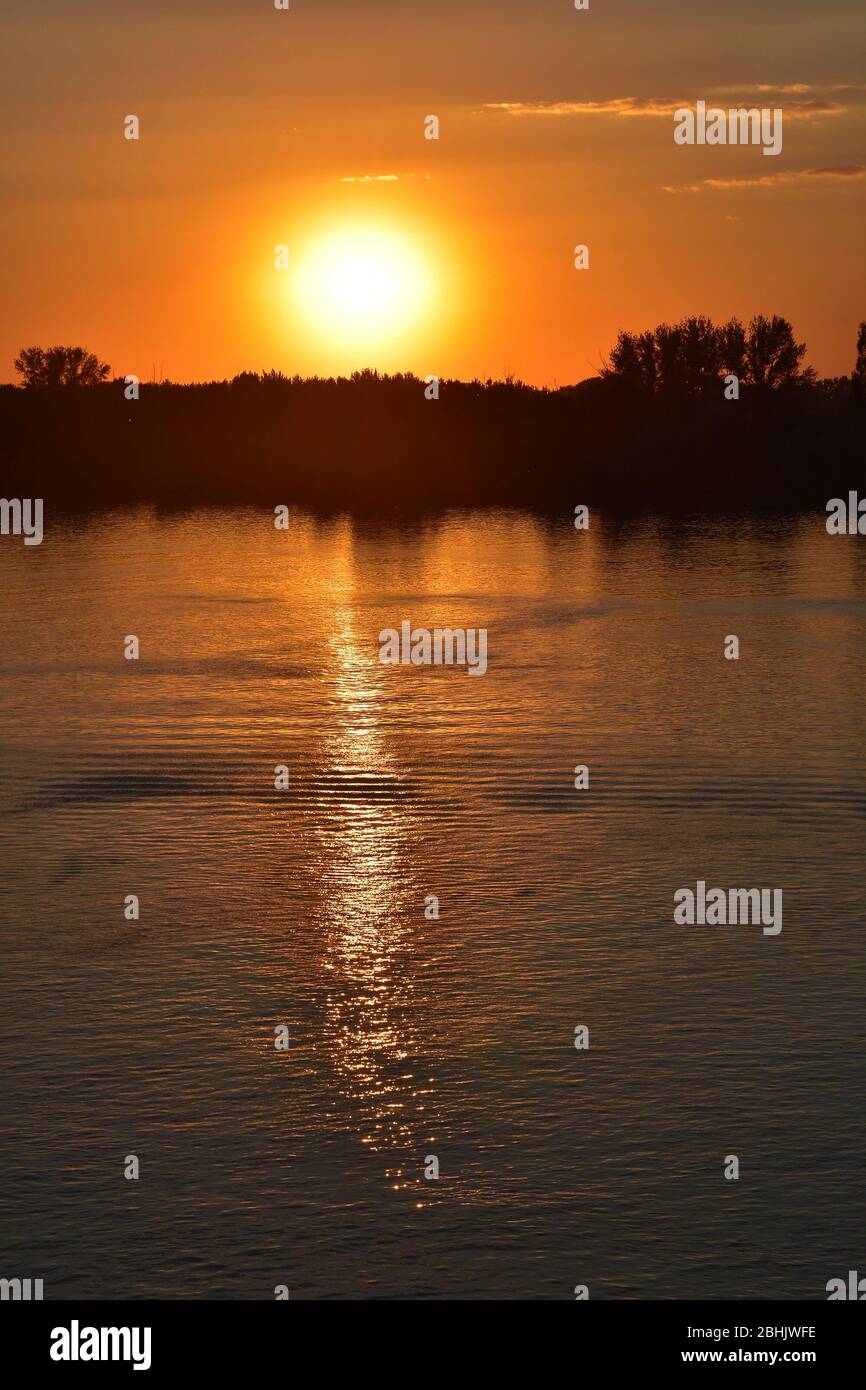 Sunset over the river. The sky and water are orange and the silhouette of the coast Stock Photo