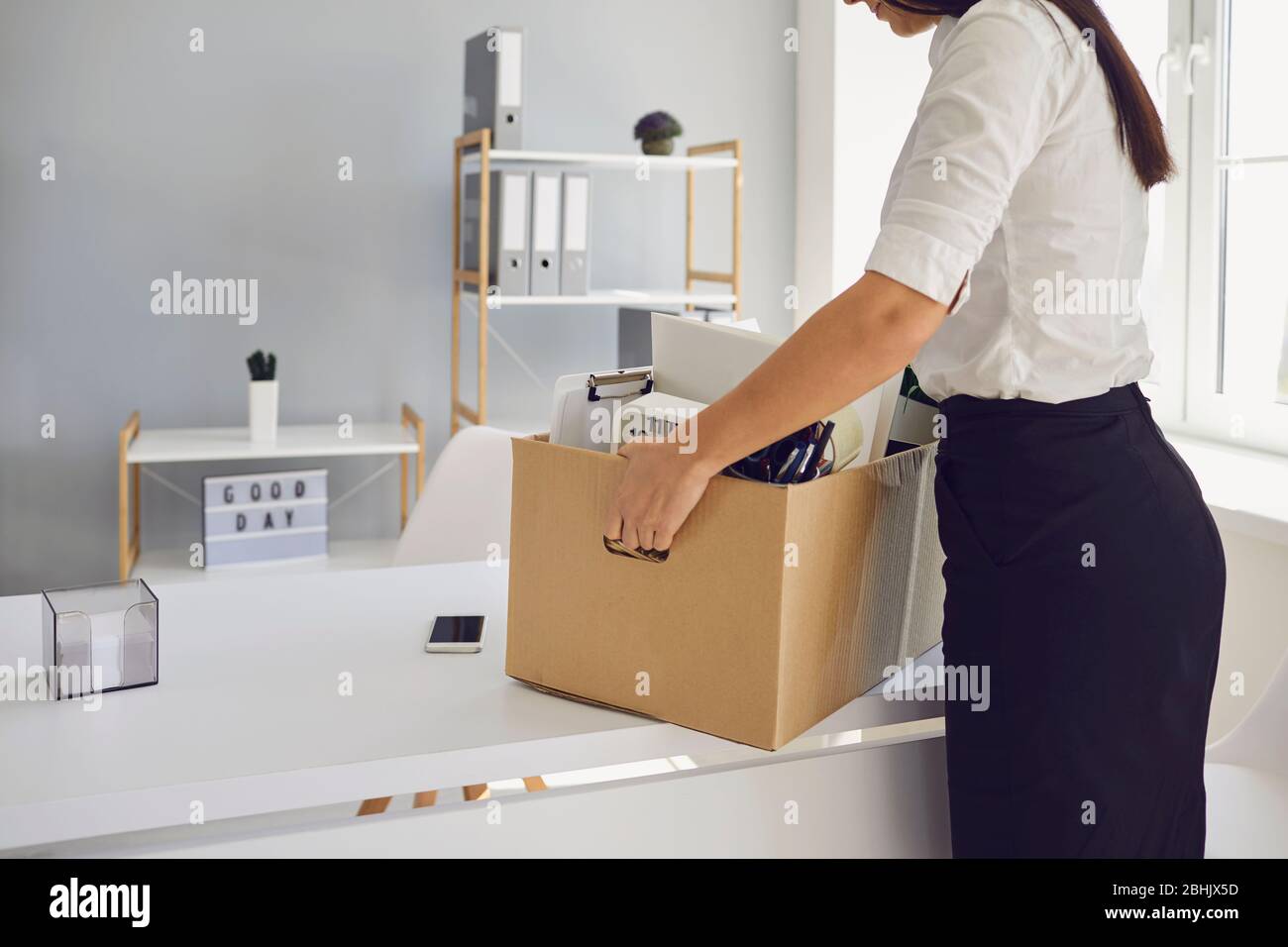 Unemployment Dismissed business woman upset with a cardboard box leaves the workplace from the office of the company. Stock Photo