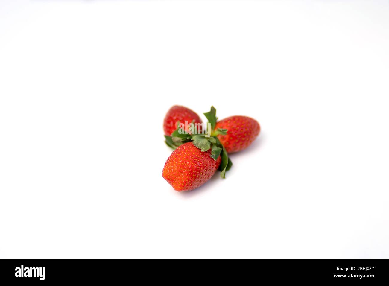 Three ripe fresh red strawberries with green leaves isolated on a white ...