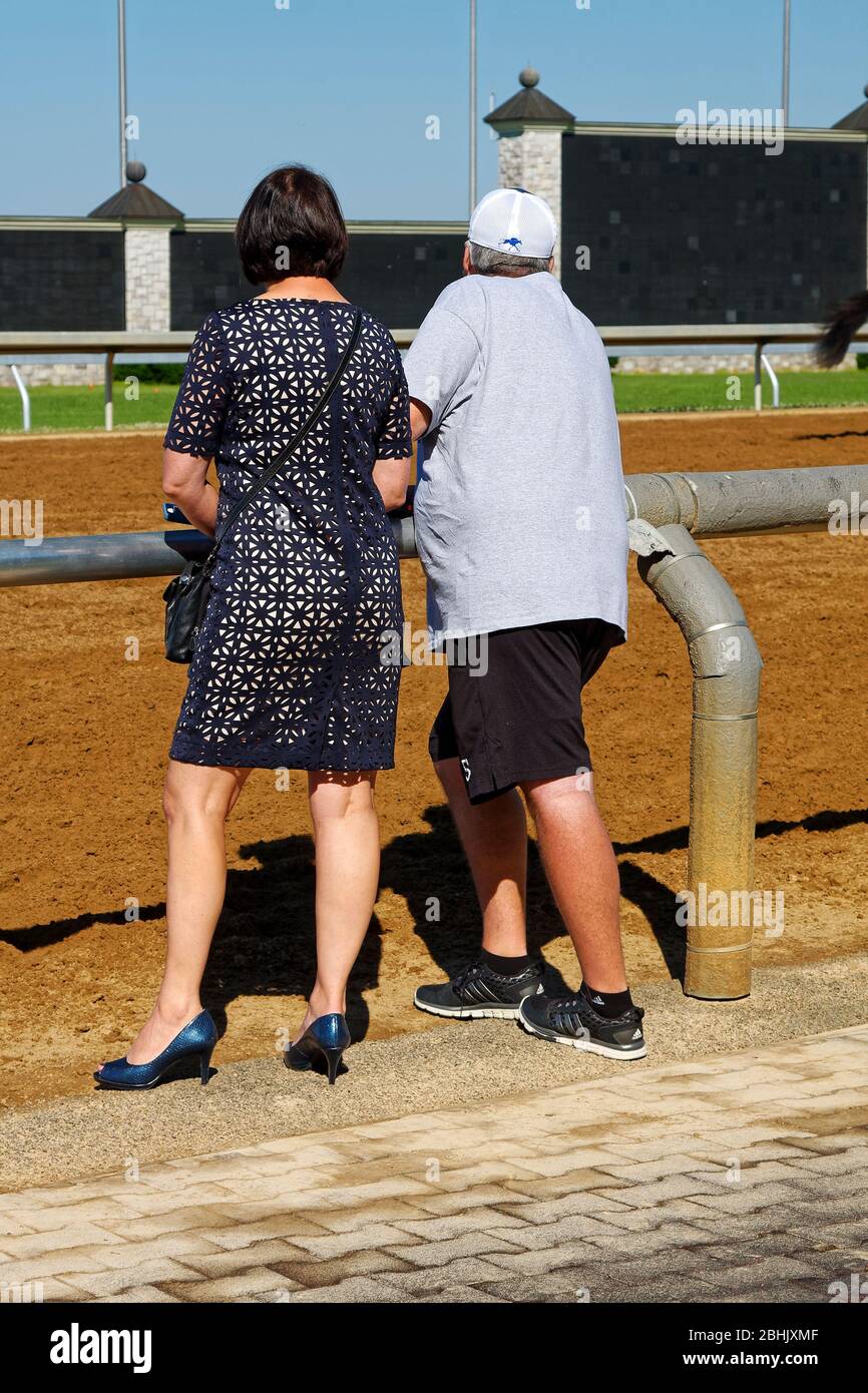 man, woman, standing at race track railing, contrasting clothing, dressy, sporty, Keeneland Racetrack; Kentucky; USA, Lexington; KY; spring Stock Photo