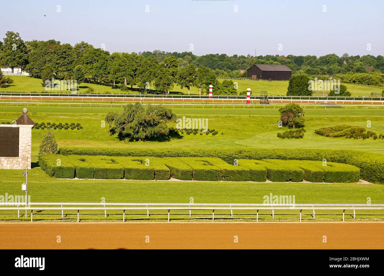 Keeneland Racetrack; early morning, golden light, name in shrubs, view from grandstand, sun, dirt track, railings, green grass, sport venue, Na Stock Photo
