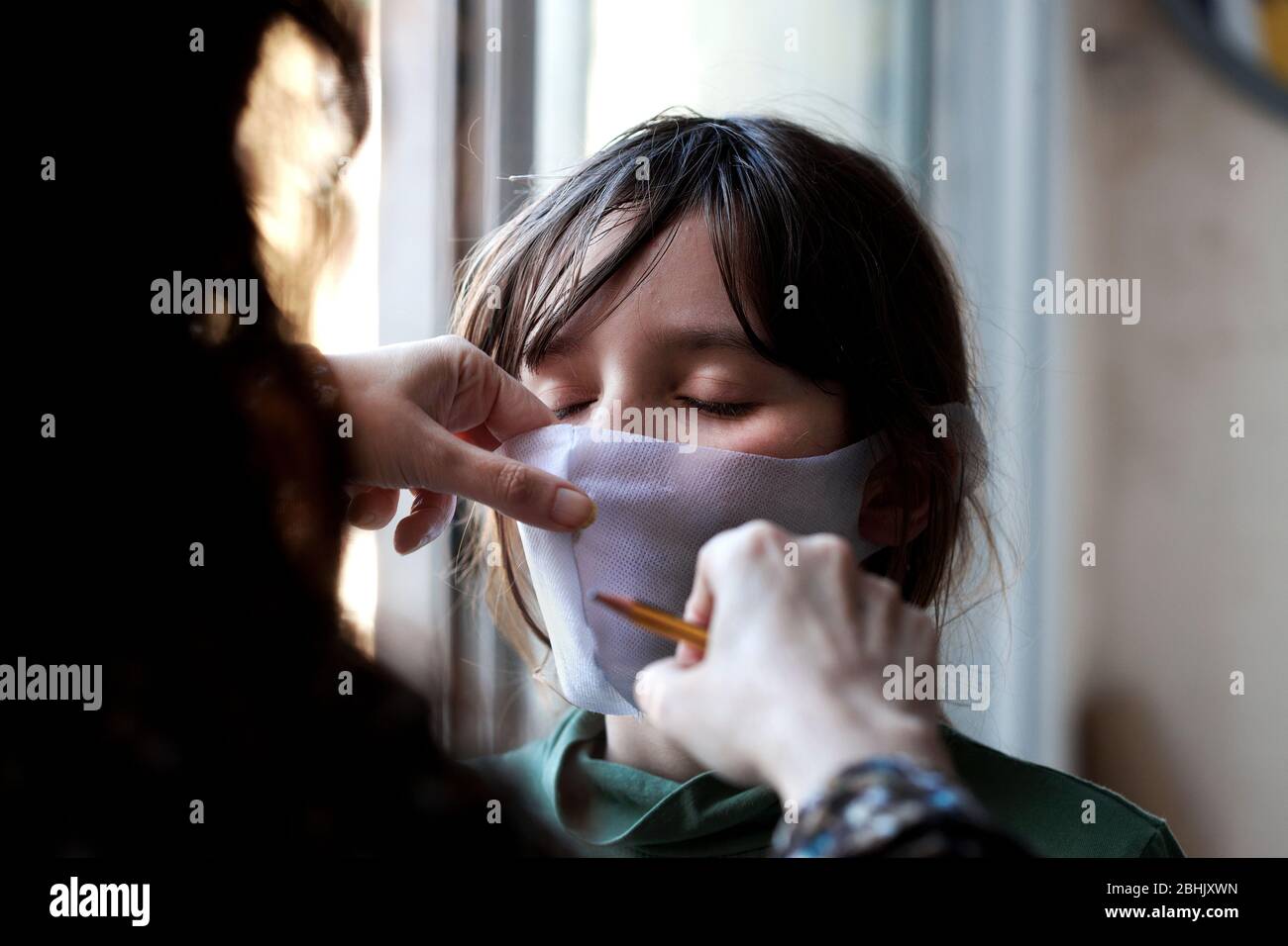 Spanish woman tailors a mask for her 11 year-old son. Stock Photo