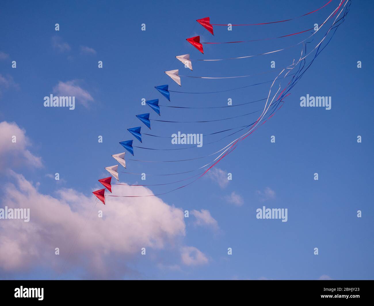 Stack of red, white an blue dual line stunt kites on a blue sky ...