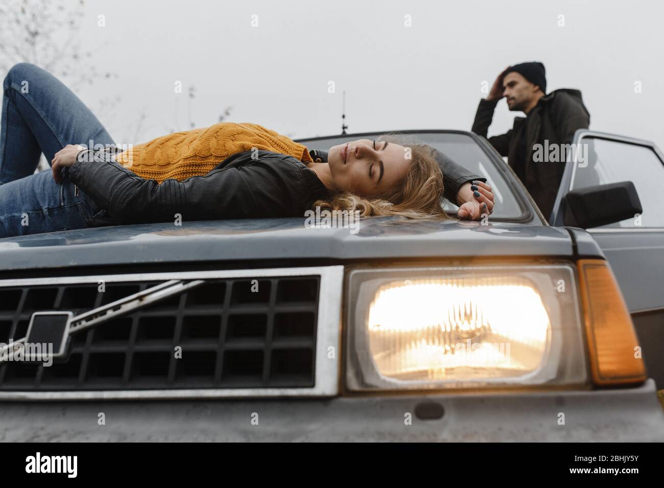 Woman lying on the car hood and man standing near the car door Stock Photo  - Alamy