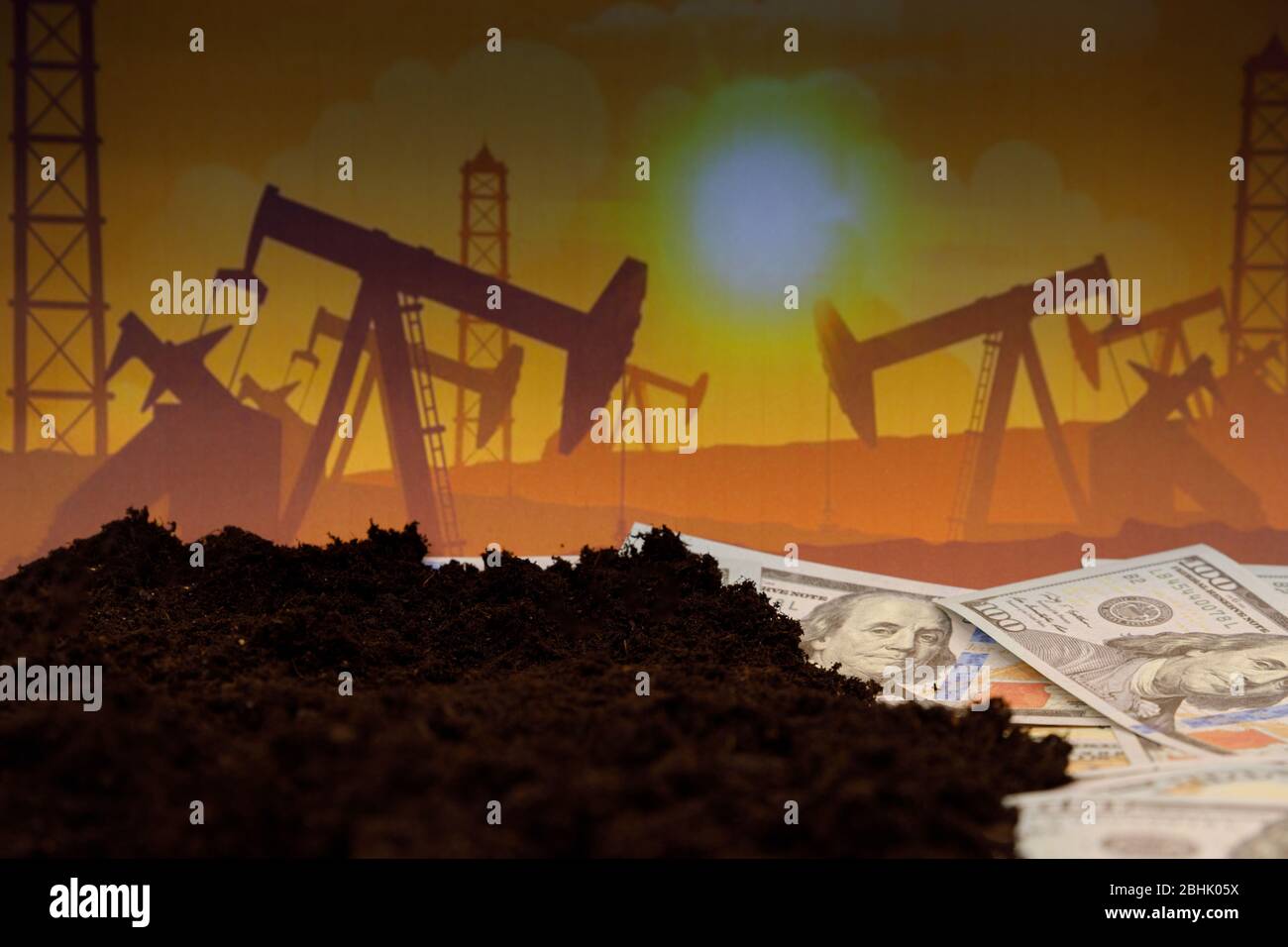 Oil industry crisis concept. Drop in crude oil prices. Hundreds of dollar bills under dirt. Stock Photo