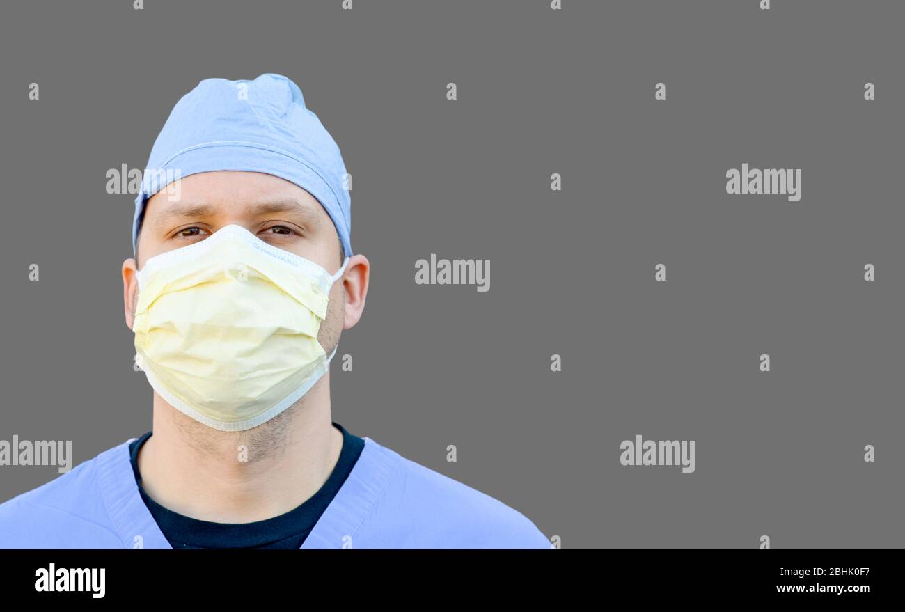 Physician wearing medical mask and scrubs isolated on gray background copy space for text. Blank coronavirus banner for adding words. Stock Photo