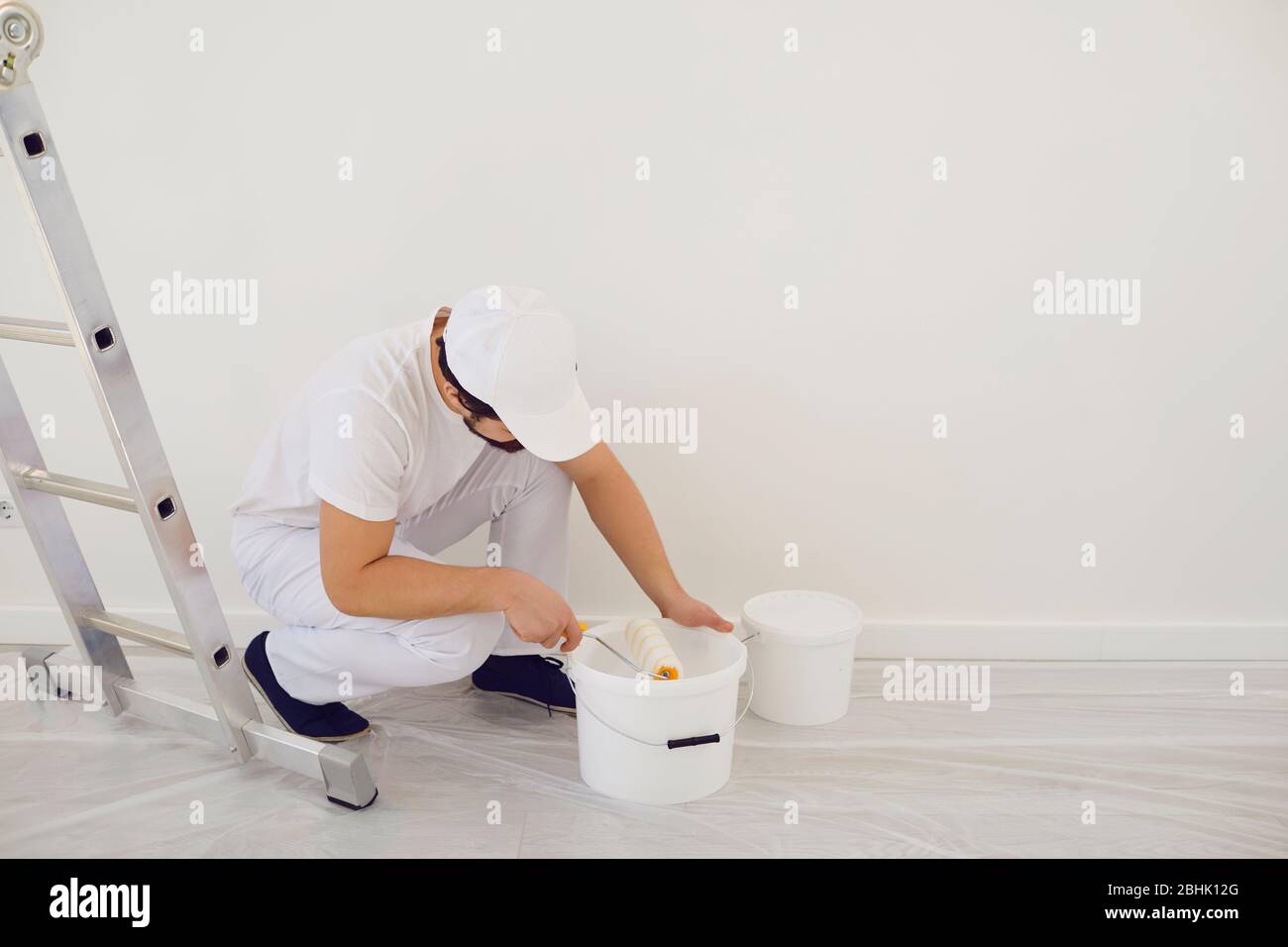 House painter in white uniform on a white background for painting in the room. Profession work painter. Stock Photo