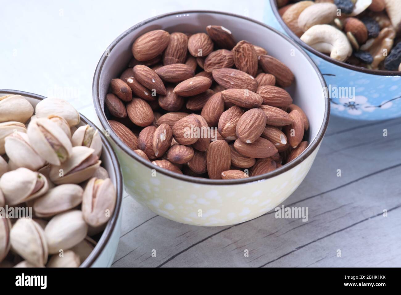 Mixed nuts in wooden bowls on wooden table . Stock Photo