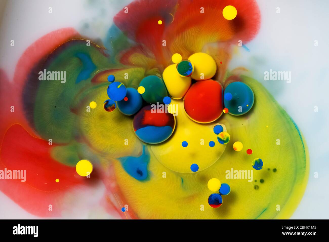 Top view of Abstract acrylic paint drops on a colorful acrylic paint background. Stock Photo