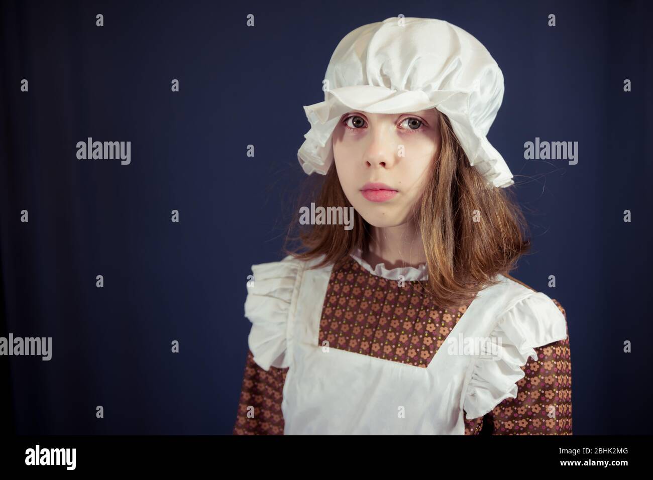 Sad girl in Victorian maid outfit with cap and apron Stock Photo