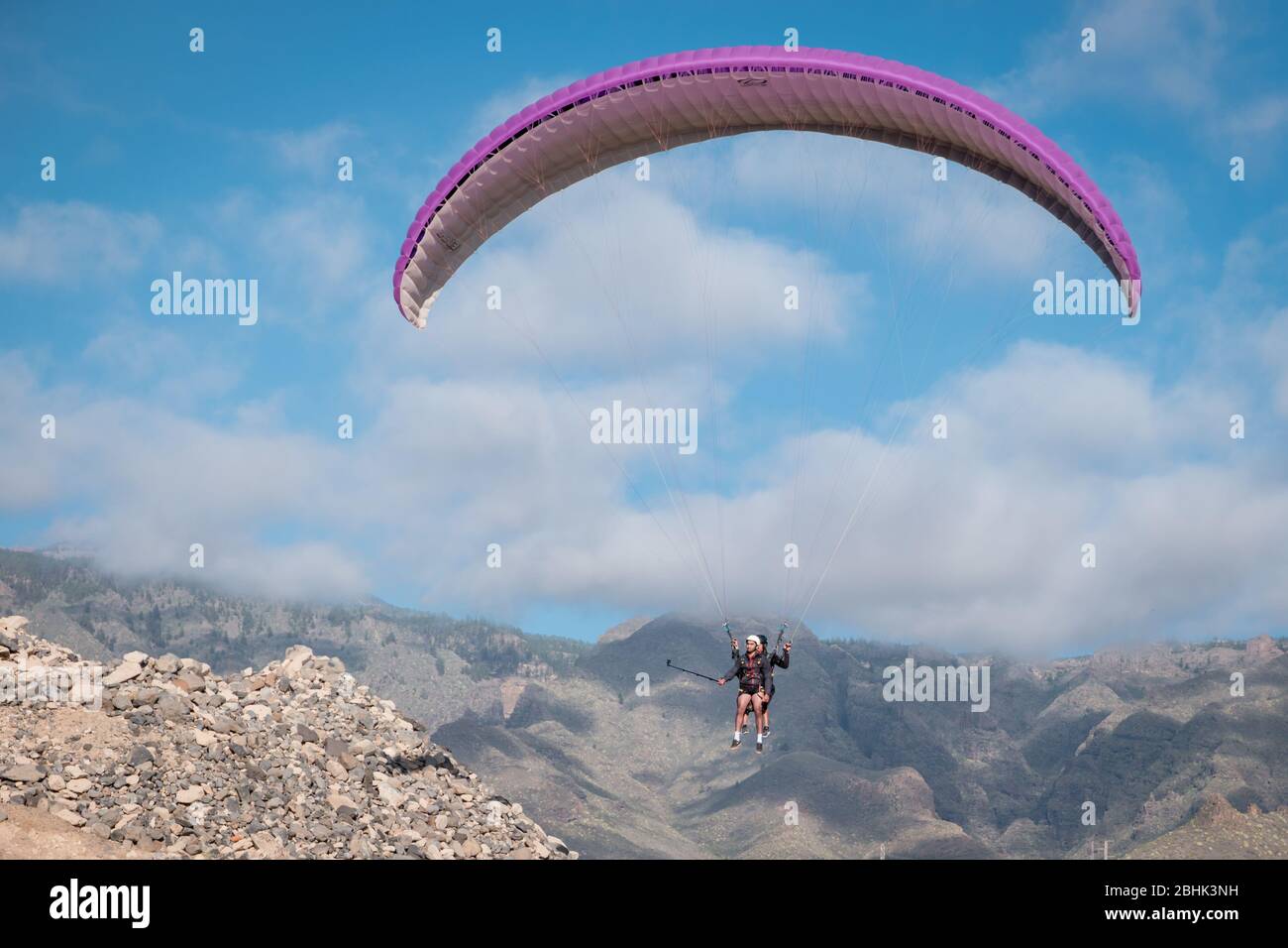 Paraglider with instructor pilot in tandem in the sky over mountains