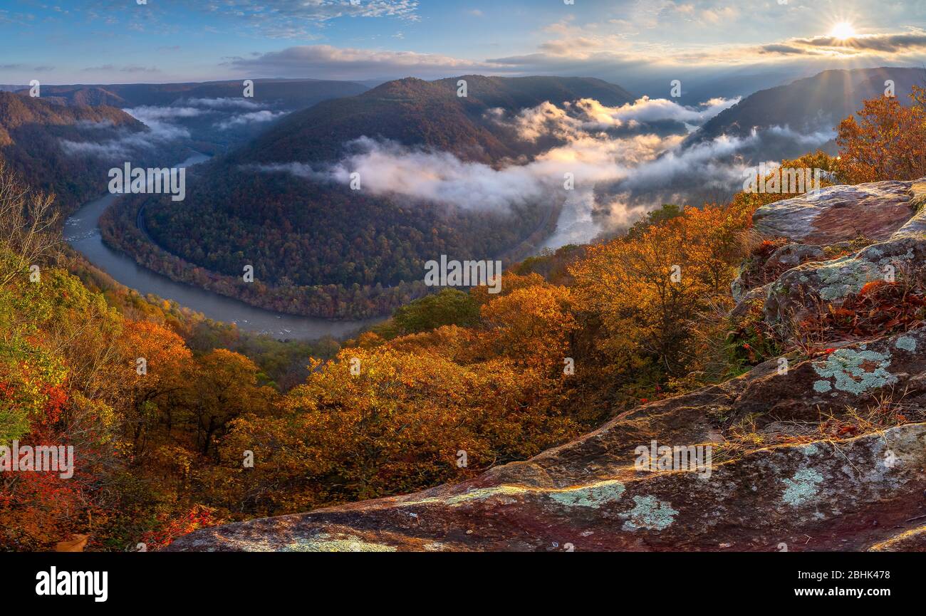 The morning sun lights up the fog and autumn foliage hanging above the New River Gorge at Grandview State Park in West Virginia. Stock Photo