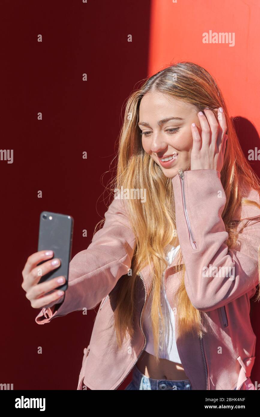 Young blond-haired Caucasian woman photographing herself with a mobile ...