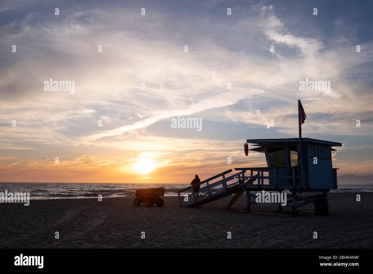 sunset over the Pacific coast with the silhouette of a lifeguard tower in Hermosa Beach, California Stock Photo