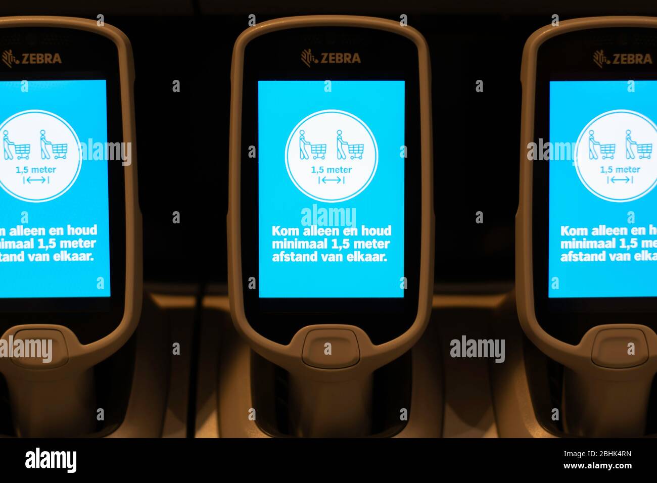Self-scanners or hand-held scanners with touchscreen in a supermarket with dutch text reminding people to keep distance of 1,5 meters Stock Photo