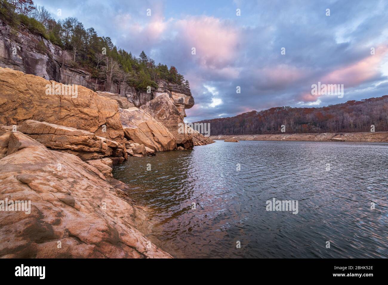 Summersville Lake drained for winter reveals house-sized boulders and high cliff lines topped with evergreens against a slightly broken, overcast sky. Stock Photo