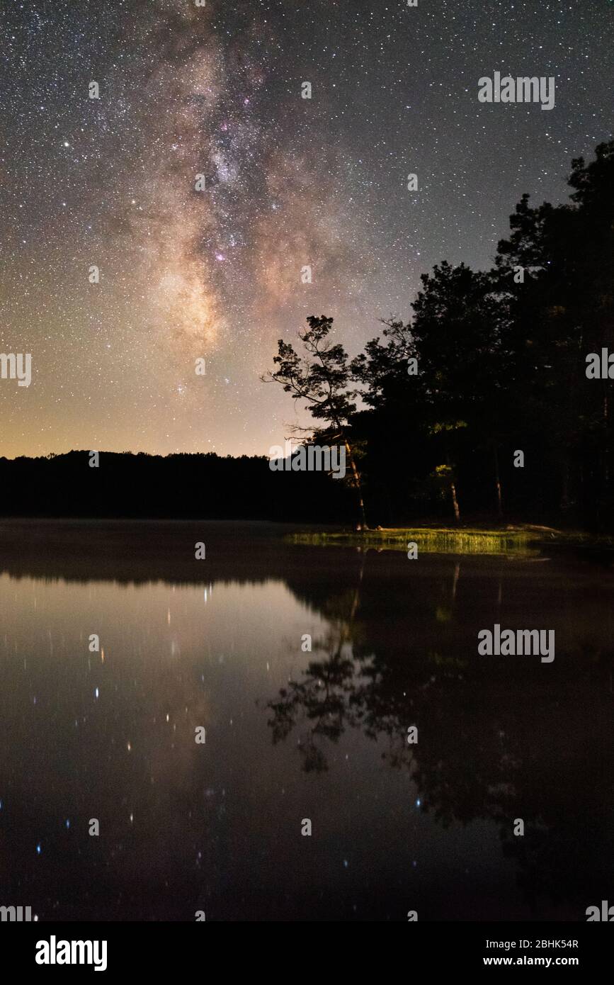 A lone tree reaches out over the glassy waters of Boley Lake behind the Milky Way at Babcock State Park, West Virginia. Stock Photo