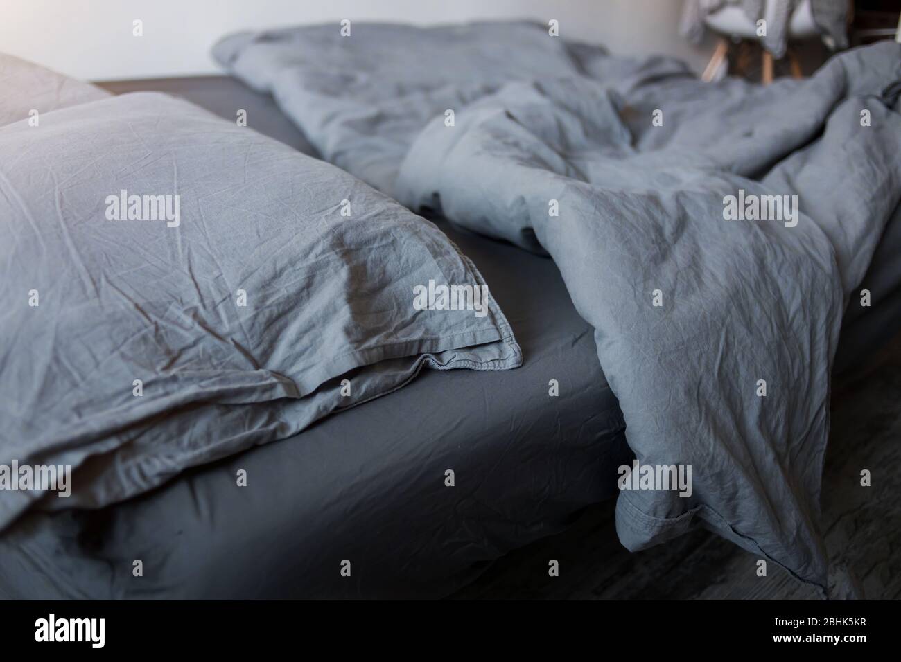 Closeup of gray pillows and blankets with a sheet on the bed Stock Photo